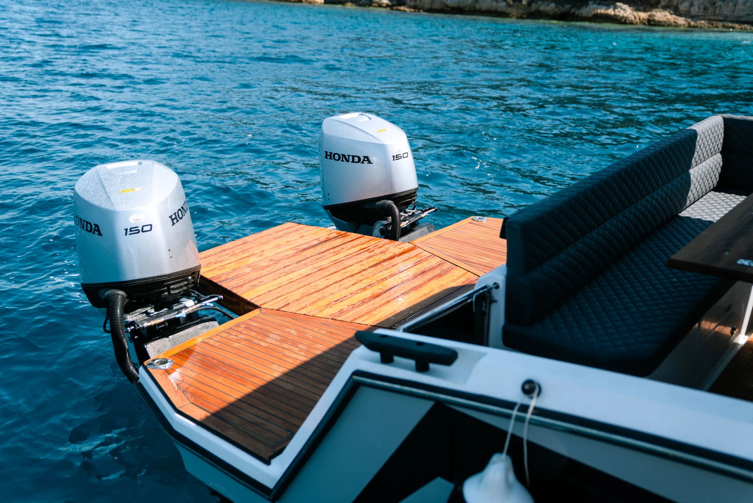 Two Honda 150 outboards behind a teak swim platform with its ladder