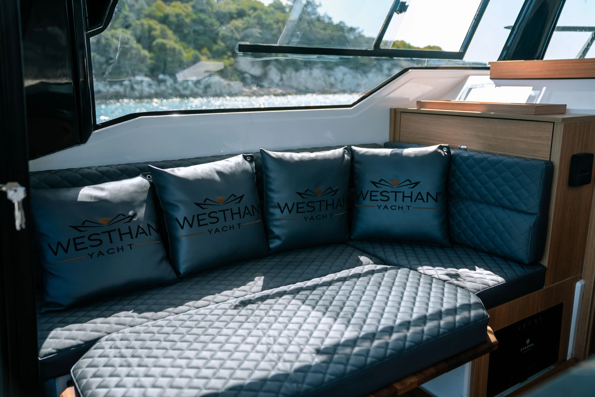 A quilted U-shaped sofa with Westhan cushions round a teak table, windows all round